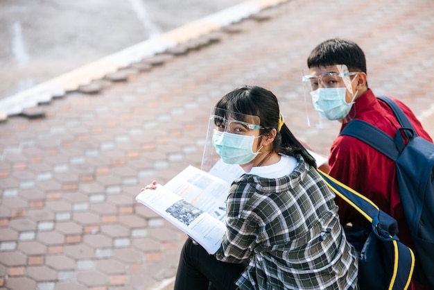 Estudiantes masculinos y femeninos con máscaras se sientan y leen libros en las escaleras