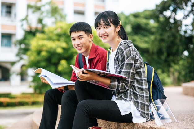 Estudiantes masculinos y femeninos sentados y leyendo libros en las escaleras.