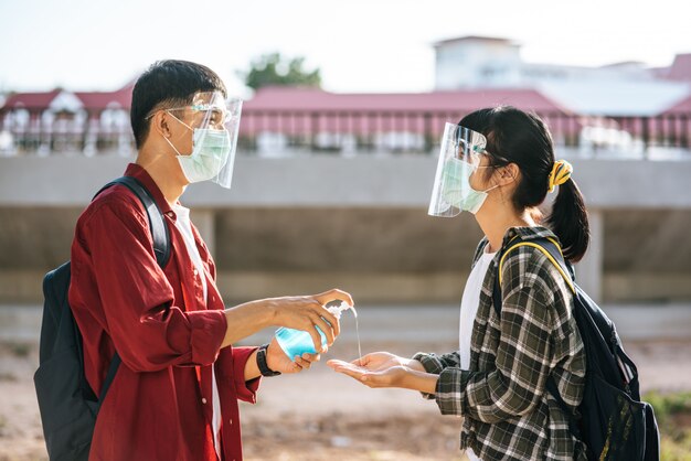 Los estudiantes masculinos y femeninos usan máscaras y exprimen el gel para lavarse las manos.