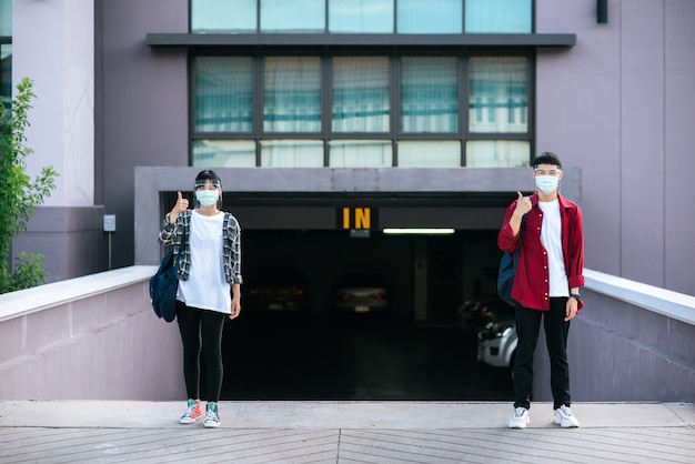 Los estudiantes masculinos y femeninos usan máscaras y se paran frente a la universidad.