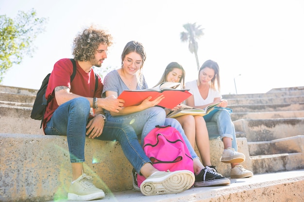 Foto gratuita estudiantes con mochila leyendo en pasos