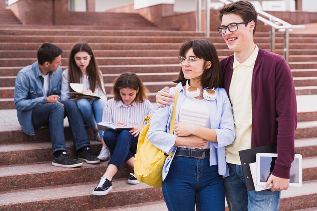 Estudiantes parados abrazando y sosteniendo libros