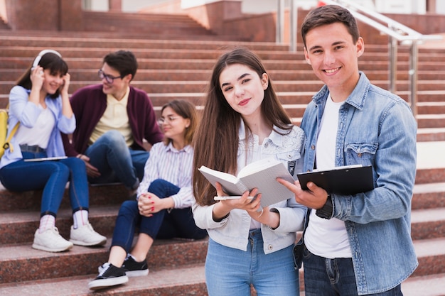 Estudiantes de pie con libros abiertos y mirando a cámara Foto Premium 