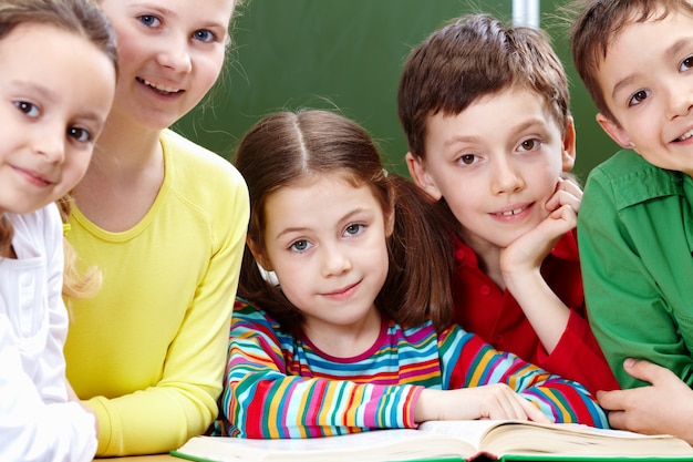 Estudiantes de primaria positivos leyendo un libro en clase