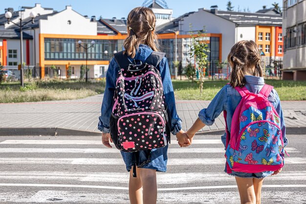 Los estudiantes de primaria van a la escuela tomados de la mano el primer día de clases de regreso a la escuela