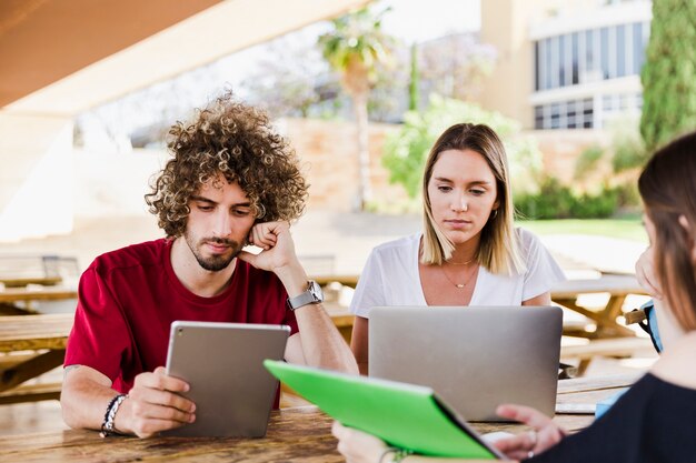 Estudiantes que usan dispositivos digitales en el parque