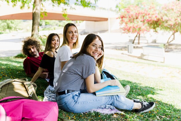 Estudiantes riendo sentados en el suelo del parque