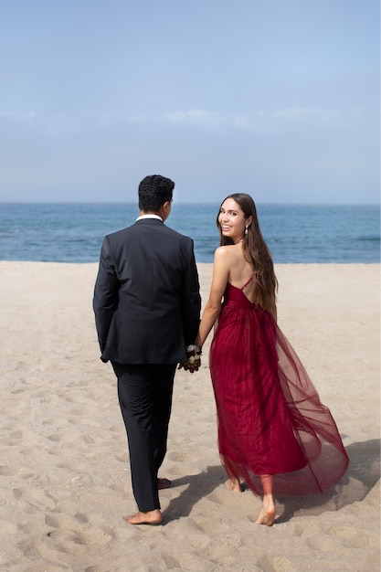 Estudiantes en ropa de graduación en la playa.