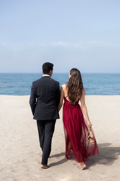 Estudiantes en ropa de graduación en la playa.