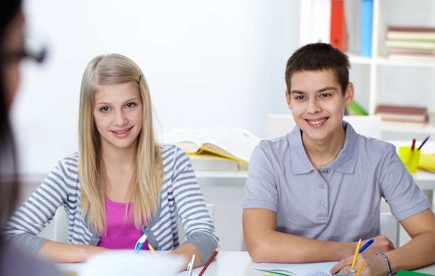 Estudiantes sentados y escuchando a la profesora en clase