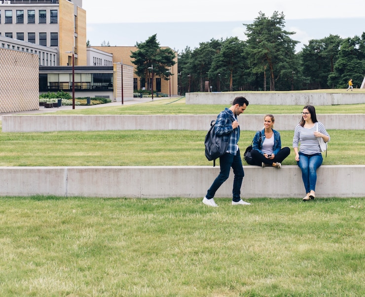 Foto gratuito estudiantes sentados en el patio de la universidad
