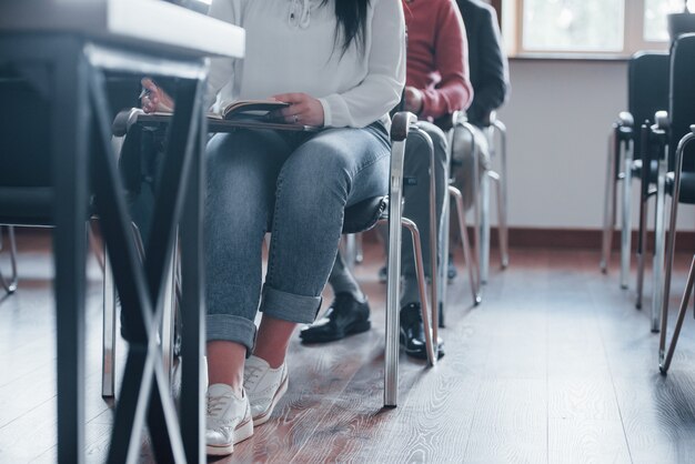 Estudiantes sentados en sillas. Grupo de personas en conferencia de negocios en el aula moderna durante el día