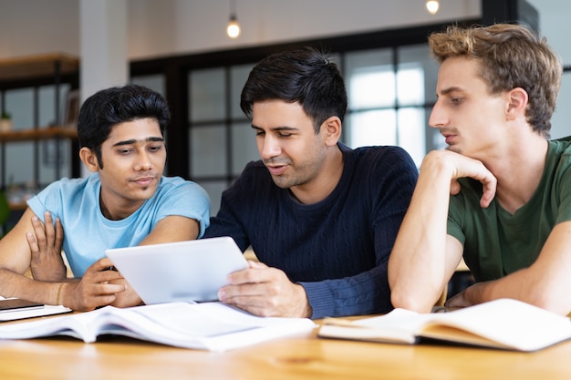 Estudiantes serios que usan tabletas y analizan información