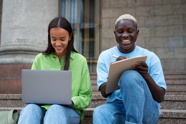 Estudiantes sonrientes aprendiendo en la vista frontal de las escaleras