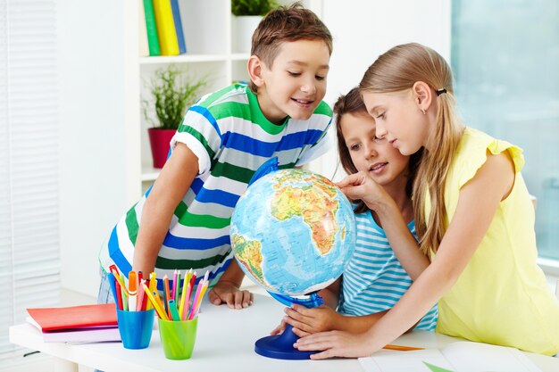 Estudiantes sonrientes mirando el globo terráqueo