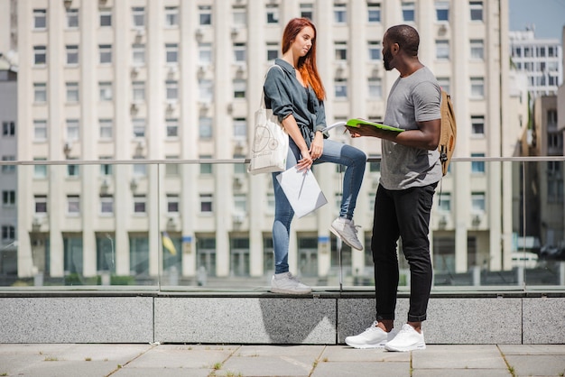 Estudiantes sosteniendo cuadernos hablando en la calle