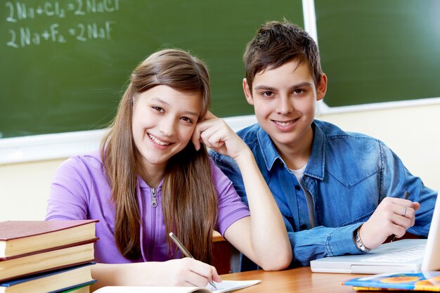 Estudiantes trabajando juntos con la pizarra de fondo