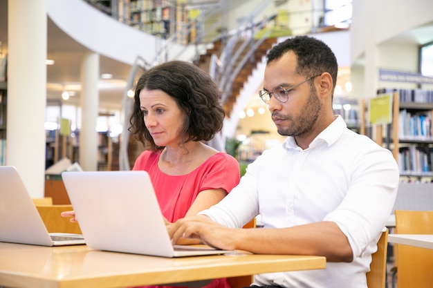 Estudiantes universitarios enfocados que trabajan en la biblioteca