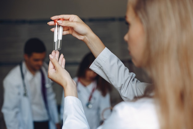 Estudio de hombres y mujeres en batas de hospital. Enfermera con tubos de ensayo.