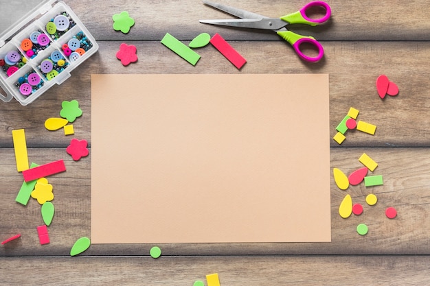 Etiqueta engomada colorida con diversa forma cerca del papel marrón en la mesa de madera