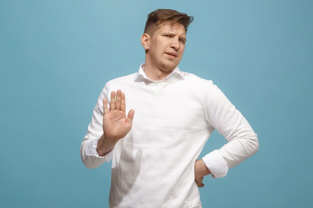 Ew. Es tan asqueroso. Hombre joven con expresión de disgusto rechazando algo. Concepto de repugnancia. Joven emocional. Las emociones humanas, el concepto de expresión facial. Estudio. Aislado en color azul de moda