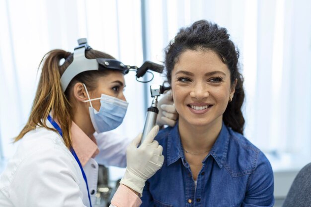 Examen de audición Médico otorrinolaringólogo revisando el oído de la mujer usando otoscopio o auriscopio en la clínica médica