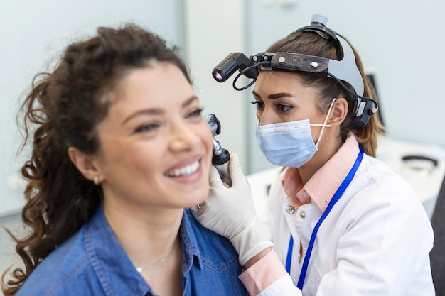 Examen de audición Médico otorrinolaringólogo revisando el oído de la mujer usando otoscopio o auriscopio en la clínica médica