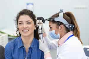 Foto gratuita examen de audición médico otorrinolaringólogo revisando el oído de la mujer usando otoscopio o auriscopio en la clínica médica