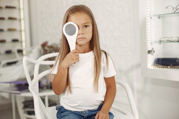 Examen y examen de la vista para niños. Niña con chequeo ocular, con foróptero. Examen de la vista para niños