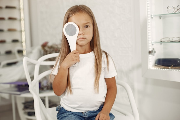 Examen y examen de la vista para niños. Niña con chequeo ocular, con foróptero. Examen de la vista para niños