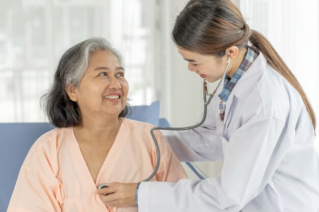 Examen médico Senior paciente femenino de edad avanzada en pacientes en cama de hospital - concepto senior médico y sanitario