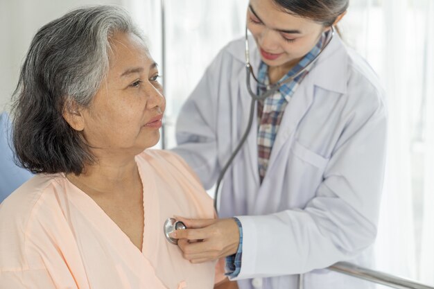 Examen médico Senior paciente femenino de edad avanzada en pacientes en cama de hospital - concepto senior médico y sanitario