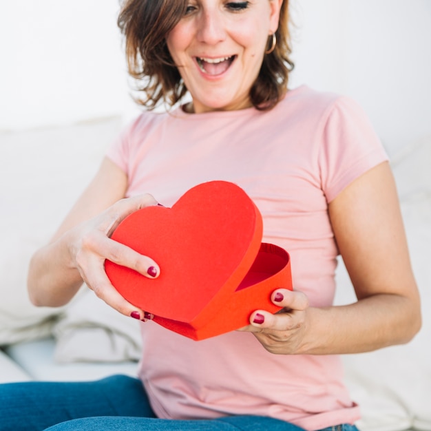 Excitada mujer abriendo caja en forma de corazón