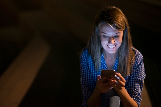 Excited hermosa chica recibiendo un mensaje sms con buenas noticias en un teléfono móvil fuera