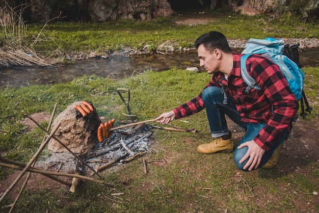 Foto gratuita excursionista cocinando salchichas