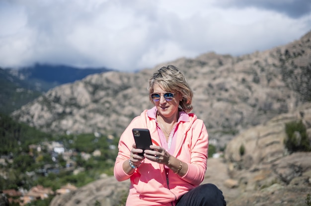 Excursionista femenina usando su teléfono y tomando fotografías de la hermosa vista