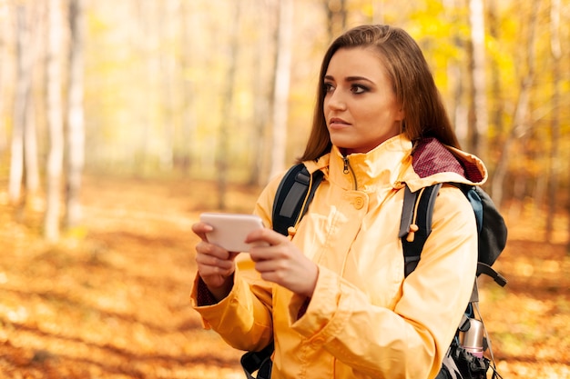 Excursionista joven confundido con teléfono inteligente en el bosque