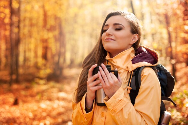 Excursionista mujer sonriente tiene un descanso para tomar una bebida caliente