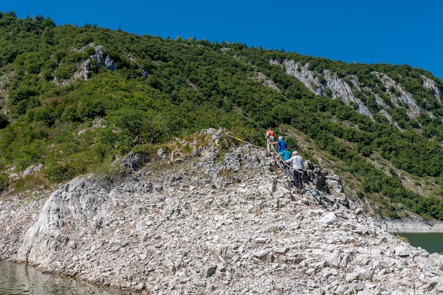 Excursionistas subiendo la colina rocosa bajo el cielo azul