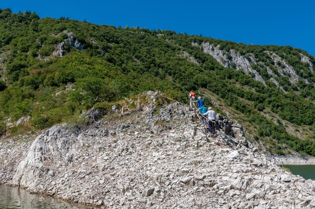 Excursionistas subiendo la colina rocosa bajo el cielo azul