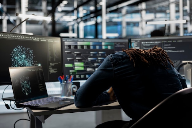 Exhausted server farm engineer falls asleep while looking at data analysis graph