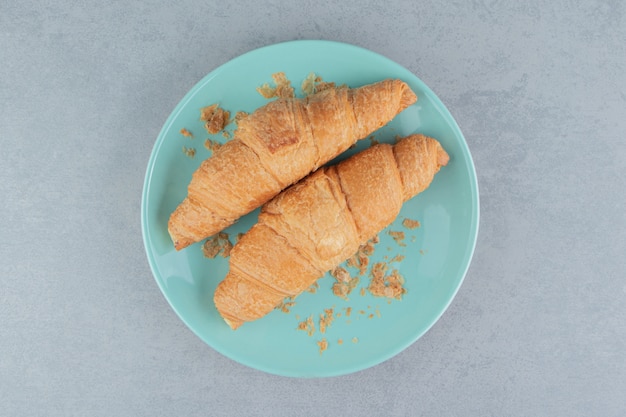 Una exhibición de croissant en placa sobre el fondo de mármol. Foto de alta calidad