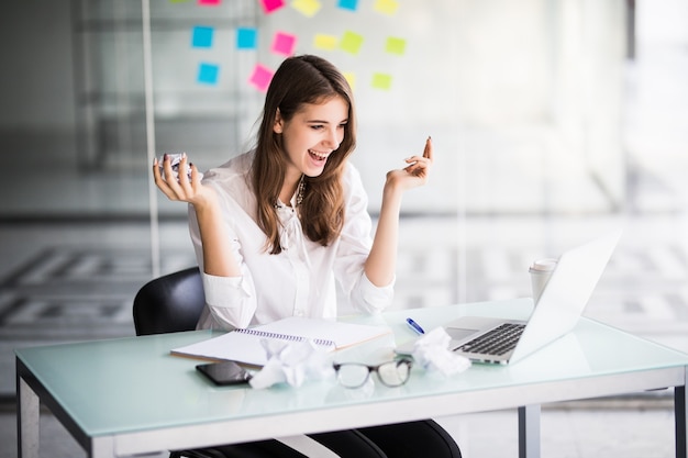 Exitosa empresaria trabajando en equipo portátil en su oficina vestida con ropa blanca