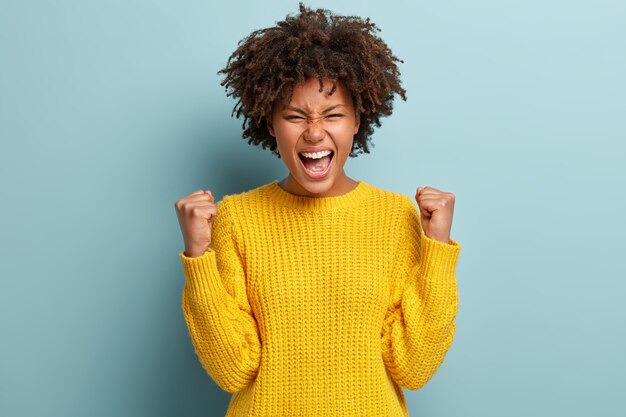 Exitosa estudiante de piel oscura feliz de obtener una beca, aprieta los puños, logra el objetivo