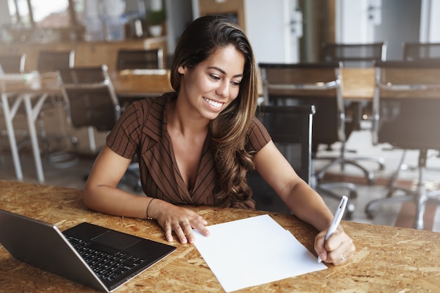 y exitosa mujer hispana sonriendo trabajando en cafe