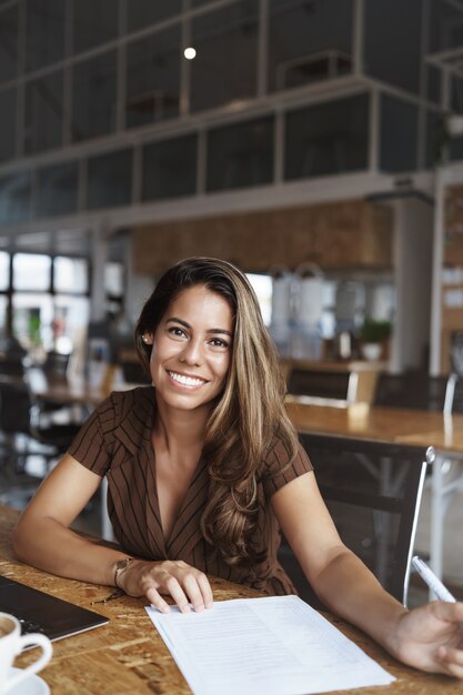 y exitosa mujer hispana sonriendo trabajando en cafe