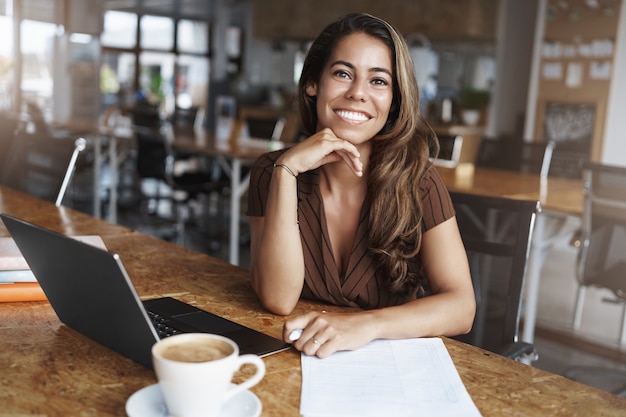 y exitosa mujer hispana sonriendo trabajando en cafe