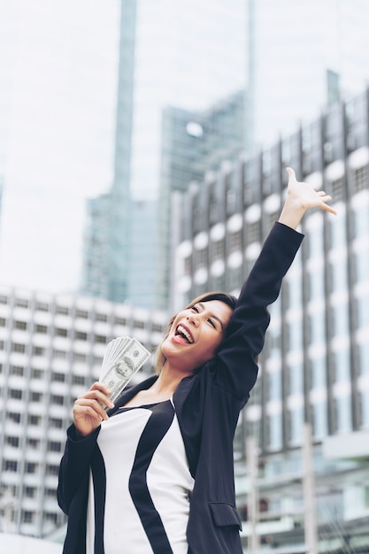 Exitosa mujer de negocios asiática hermosa con dinero en billetes de dólares estadounidenses en la mano, concepto de negocio