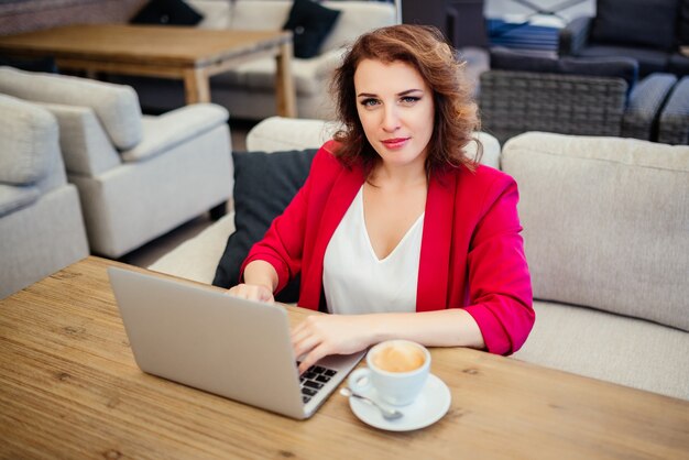 Exitosa mujer de negocios trabajando en la computadora portátil en el salón de café.