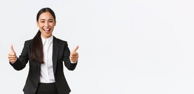Exitosa y optimista mujer de negocios asiática mostrando pulgares hacia arriba y sonriendo feliz y alegre señora gerente en bu